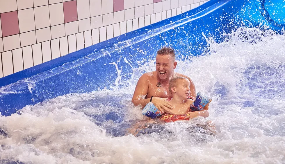 Vader en zoon die waterglijbaan afgaan.webp